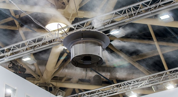 Eine Luftbefeuchtungsanlage in einer Halle, an einem Träger hängend, versprüht Wasser.